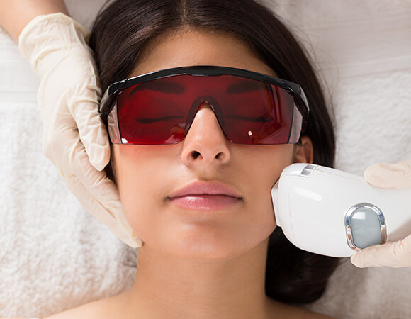 Woman wearing protective glasses undergoing intense pulsed light treatment at MediZen Institute