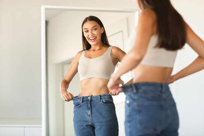 Woman measuring waist after weight loss at MediZen Institute